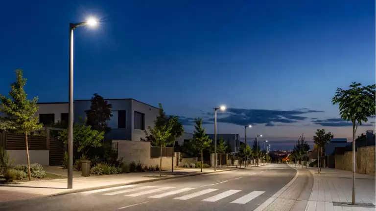 Farolas viales LED iluminando una calle residencial al anochecer Farolas viales LED iluminando una calle residencial al anochecer