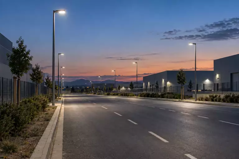 Farolas LED iluminando un vial industrial al amanecer Farolas LED iluminando un vial industrial al amanecer